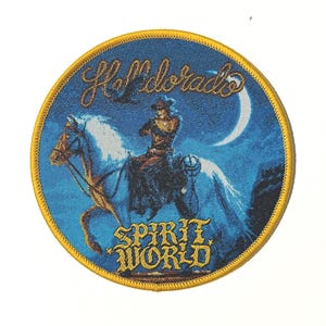 Op de afbeelding: Ronde patch met een blauwe achtergrond en een gouden rand. De patch toont een ruiter op een wit paard, een halve maan en de woorden "Hell Dorado" en "Spirit World" in gouden letters. Een vogel vliegt boven de ruiter.