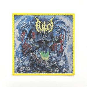 Peut inclure: Écusson carré avec une bordure jaune, présentant une illustration détaillée en bleu et blanc. L'œuvre représente des figures grotesques, une figure centrale semblable à un démon et le texte "OLD" en jaune. La phrase "OPENING THE HELL GATES" est en bas.