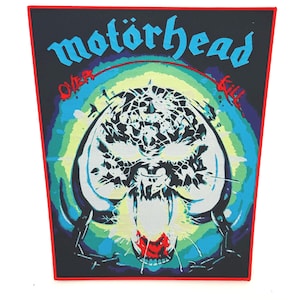 May include: A black patch with a red border featuring the band name "motörhead" in blue, above a skull graphic. The skull is white with black details, set against a colorful background of blue, green, and yellow. The text "Over Kill" is also present.