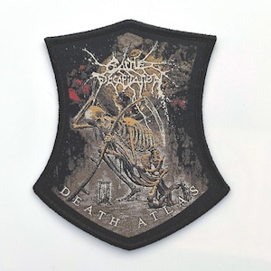 May include: A black and gray patch with a shield shape. The patch features a skeleton figure with a scythe, the band name, and the words "DEATH ATLAS". The design has a distressed, vintage aesthetic.