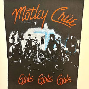 May include: Black and white image of a band, Motley Crue, on motorcycles with the words "Girls Girls Girls" in red below.