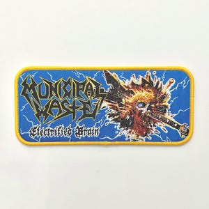 May include: A blue and yellow embroidered patch featuring the band name "Municipal Waste" and the album title "Electrified Brain". The patch depicts a skull with a guitar piercing through it.