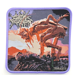 May include: Square patch with a purple border featuring a detailed illustration of a creature with a reddish-brown body and a dark background. The text "TERRASITE" is at the bottom, and the top has illegible text.