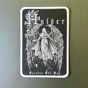 以下が含まれることがあります： ゴシック体で「Hulder」の文字と、詳細な翼を持つローブを着た人物のイラストが描かれた、長方形の白黒パッチ。「...Hearken The End...」の文字が下部にあります。白い縁取りがあります。