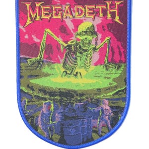May include: A rectangular patch with a blue border displays the band name "MEGADETH" in yellow. The patch shows a green skeleton rising from a toxic green pool, with figures in hazmat suits below.