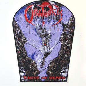 以下が含まれることがあります： 紫色の背景に黒と白のパッチ。パッチには、バンド「Obituary」のバンドロゴと「Cause of Death」の文字が書かれています。