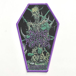Puede incluir: Un parche en forma de ataúd con fondo negro y borde morado. El parche presenta una ilustración verde y morada de una figura esquelética y las palabras "ENTOMBED IN PUTREFACTION".