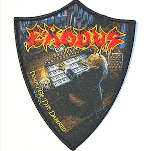 以下が含まれることがあります： 赤と黄色の炎のような文字で「EXODUS」という文字が入ったシールド型のパッチ。キーボードを演奏している人のイラストが描かれており、「Tempo Of The Damned」という文字が入っています。パッチには黒い縁取りがあります。