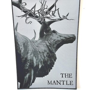 Puede incluir: Un parche rectangular con borde negro presenta una ilustración en escala de grises de un ciervo con grandes cuernos. La palabra "ASLOOD" está escrita encima de la cabeza del ciervo en una fuente estilizada, y las palabras "THE MANTLE" están debajo.