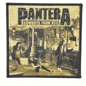 May include: Square patch with the band name "PANTERA" and the text "COWBOYS FROM HELL". The patch has a black border and a sepia-toned image of the band performing. The image is on a textured, tan background.