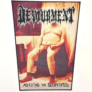 May include: A rectangular patch with a maroon border features the word "DEVOUMENT" in a dripping, gothic font above a headless nude figure. The text "MOLESTING THE DECAPITATED" is printed below the figure.