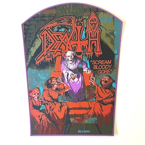 May include: A rectangular patch with a purple border features a gothic illustration. The image includes the word "DEATH" in red, a skeletal figure, and the text "SCREAM BLOODY GORE." The artwork depicts figures in red robes and a skull-faced figure.