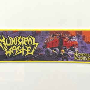 May include: A yellow and purple embroidered patch with the text "Municipal Waste" and a red truck with the text "Hazardous Mutation".
