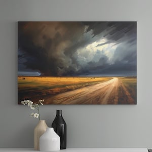 May include: A modern living room interior with a large canvas painting of a stormy sky over a dirt road. The painting is hanging on a light gray wall above a white media console. A gray armchair with a wooden base sits in front of a coffee table with a black metal base and a gray marble top. Two wooden boxes are stacked on the table.