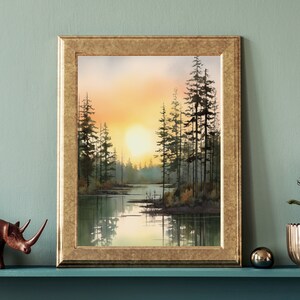May include: A framed watercolor painting of a forest scene with a lake in the foreground. The sun is setting behind the trees, casting a warm glow over the landscape.