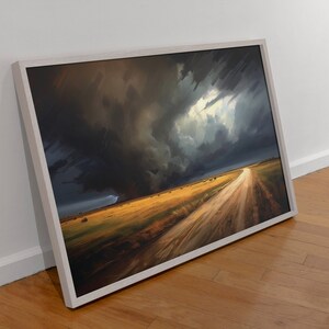 May include: A framed painting depicting a dirt road leading into a field with a dramatic stormy sky overhead. The sky is dark and stormy with a bright light shining through the clouds. The field is a golden yellow color.