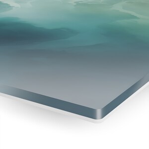 May include: A close-up of a teal and gray abstract painting on a canvas with a white frame.