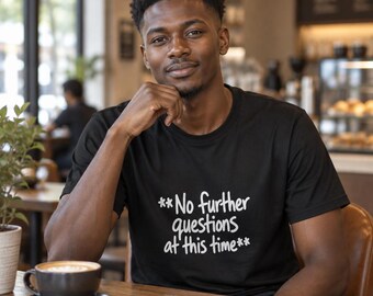 Può includere: Una t-shirt nera a maniche corte con il testo bianco "**No further questions at this time**" stampato sul davanti. Il capo presenta un classico girocollo e una vestibilità standard, con una scritta chiara e leggibile sul petto.