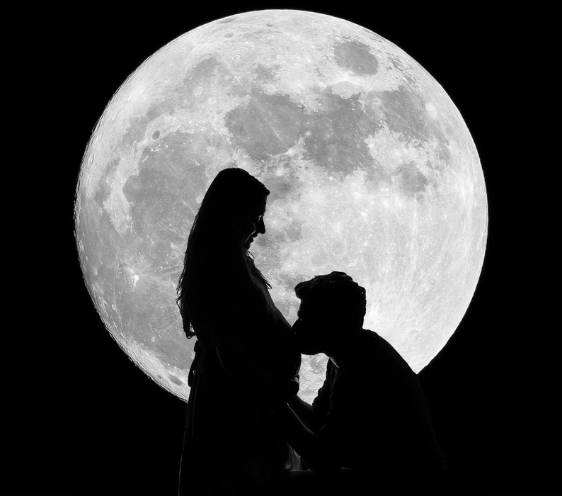 May include: A black and white silhouette of a pregnant person and a person kissing their belly, with a large full moon in the background. The image highlights the figures against the moon's bright surface and the dark sky.
