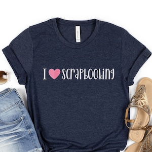 May include: A navy blue t-shirt with the text "I love scrapbooking" in white with a pink heart.
