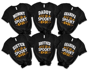 Könnte beinhalten: Sechs schwarze T-Shirts mit weißem und orangefarbenem Text, der lautet: "Mommy of the Spooky One", "Daddy of the Spooky One", "Grandpa of the Spooky One", "Sister of the Spooky One", "Brother of the Spooky One" und "Grandma of the Spooky One".