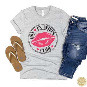 May include: Grey t-shirt with a black circle graphic that says "Hot Ex-Wives Club" with a pink lipstick print inside the circle.