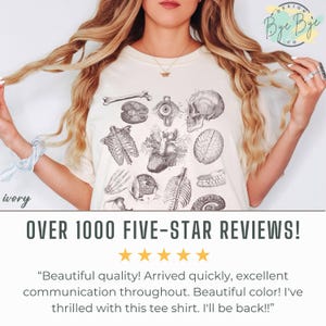 May include: Ivory t-shirt with a detailed anatomical illustration of human organs and bones, including a skull, heart, and brain. The design also features the text "Bye Bye" and "OVER 1000 FIVE-STAR REVIEWS!"