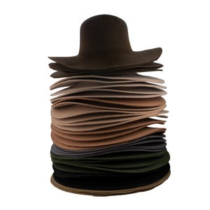Peut inclure: Une pile de chapeaux en feutre de différentes couleurs, dont le marron, le beige, le gris, le vert et le noir. Les chapeaux sont disposés en pile, le plus grand chapeau étant en haut.