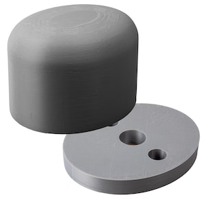 May include: A grey plastic 3D printed object with a round top and a flat base with two holes. The object is designed to be used as a connector or a spacer.