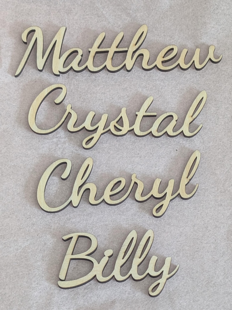 Puede incluir: Cuatro recortes de madera individuales con los nombres Matthew, Crystal, Cheryl y Billy escritos en una fuente cursiva. Cada nombre est&aacute; hecho de madera de color claro con bordes oscuros, mostrando una superficie lisa y letras conectadas.