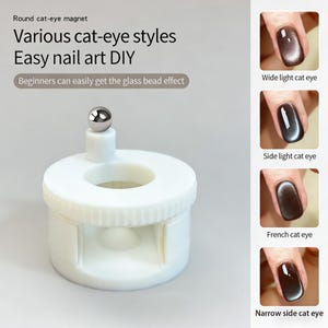 Puede incluir: Un imán redondo blanco para uñas con efecto ojo de gato. El imán tiene una bola plateada en la parte superior y está diseñado para un arte de uñas DIY fácil. La imagen muestra ejemplos de estilos de ojo de gato, incluyendo ancho, lateral y francés.