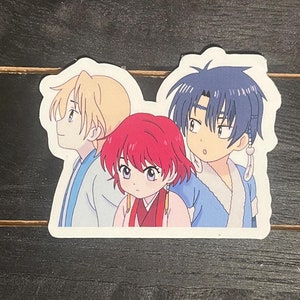 May include: A sticker featuring three anime characters. The character on the left has blonde hair and is wearing a blue and white outfit. The character in the middle has red hair and is wearing a red and gold outfit. The character on the right has blue hair and is wearing a blue and white outfit.