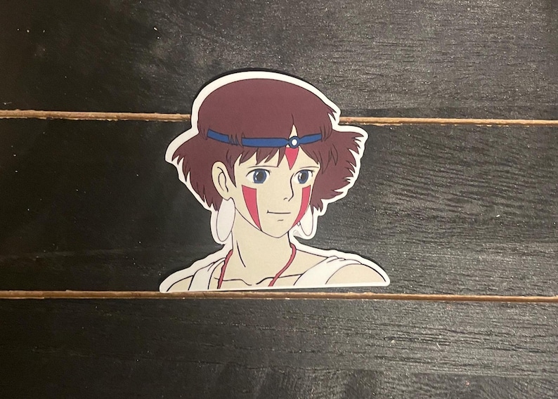 May include: A sticker featuring a cartoon illustration of a young woman with brown hair, wearing a blue headband and a red and white face paint design.