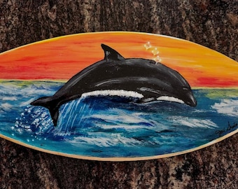Un delfino che salta nell'oceano dipinto su una piccola tavola da surf e poi ricoperto di resina