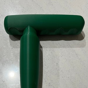 May include: A green plastic hand tool with a pointed end and a flat top. The tool is designed for planting bulbs.