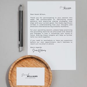 May include: A professional stationery set featuring a black pen, a letter, and a business card. The letter is addressed to Karen Wilson and includes the name "Sarah Williams, Life Coaching". The business card also displays the same name and title.
