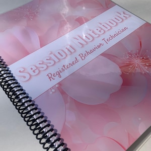 May include: A pink spiral bound notebook with a floral design and the text "Session Notebook Registered Behavior Technician".