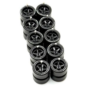 May include: A set of ten black rubber tires with white lettering, stacked in two rows of five. The tires have a five-spoke design and are designed for model cars.