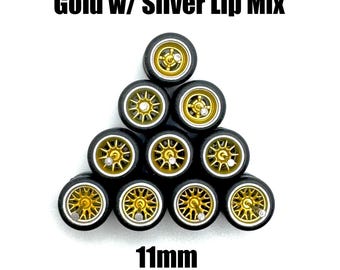 May include: A set of 11mm gold wheels with silver lips for model cars. The wheels are arranged in a pyramid shape, with the top wheel facing the viewer. The wheels are black with gold rims and silver lips.