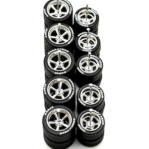 May include: A collection of miniature model car wheels. Each wheel features a silver spoke design and is mounted on a black tire. The tires have the words "EAGLE" and "GOOD YEAR" printed on the sidewalls.