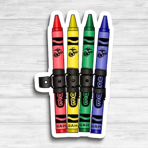 May include: Four crayons, red, yellow, green, and blue, are held together by a black strap with the word "Marine" written on it. Each crayon has a small image of the Marine Corps emblem and the word "RAH" written on it.