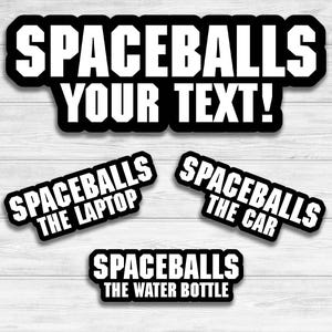 May include: Four black and white stickers with the text "Spaceballs" and different sub-text. The first sticker says "Spaceballs Your Text!" The second sticker says "Spaceballs The Laptop". The third sticker says "Spaceballs The Car". The fourth sticker says "Spaceballs The Water Bottle".
