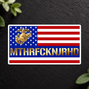May include: A rectangular sticker featuring the United States flag with a gold-colored United States Marine Corps Eagle, Globe, and Anchor emblem on the left and the gold text MTHRFCKNJRHD centered on a blue horizontal stripe.