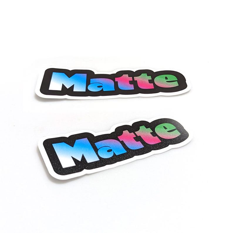 Puede incluir: Dos pegatinas con la palabra "Matte" en una fuente de degradado de colores. La pegatina superior tiene un fondo blanco con contorno negro y la pegatina inferior tiene un fondo negro con contorno blanco.
