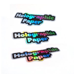 May include: Three holographic stickers with the text "Holographic Paper" in black letters with a rainbow iridescent background.