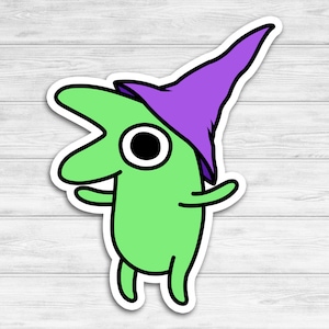 May include: A green cartoon character with a purple hat. The character has a large eye and a wide smile. The character is wearing a purple hat with a pointed tip.
