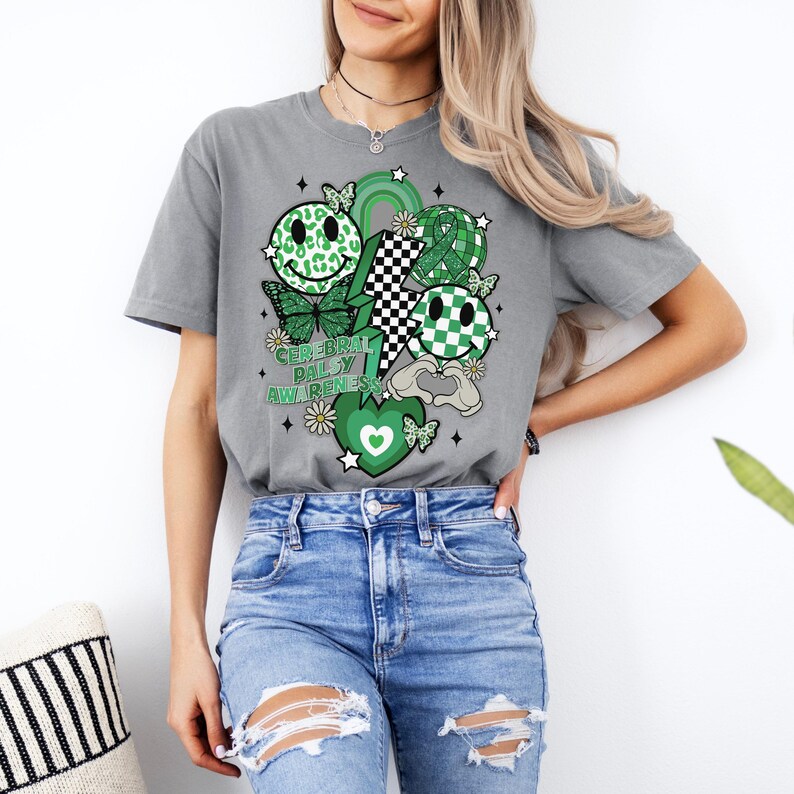 May include: A grey t-shirt with a green and white design featuring a lightning bolt, smiley faces, butterflies, and the text "Cerebral Palsy Awareness".