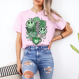 May include: A pink t-shirt with a green and black design featuring smiley faces, butterflies, a lightning bolt, and the text "Cerebral Palsy Awareness".