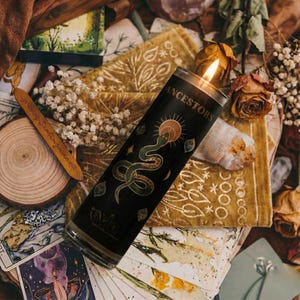 “Ancestor veneration candle surrounded by tarot cards, crystals, dried roses, herbs, and gold embroidered cloth, black ritual candle for meditation, ancestral connection, and altar décor.”