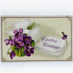 Cartolina d'epoca del 1911 con stampa in rilievo di Pasqua raffigurante un libro di auguri pasquali e fiori viola con un francobollo Benjamin Franklin da 1 centesimo.
